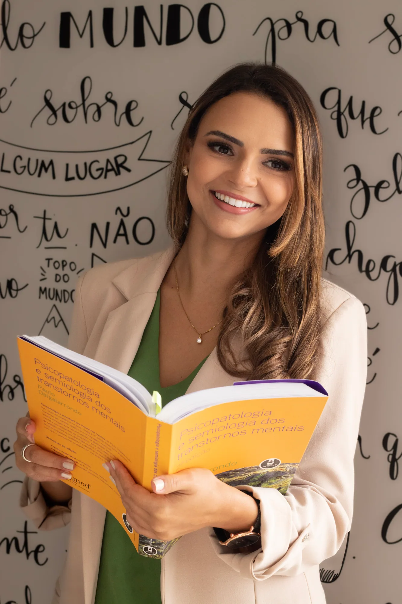 Dra. Letícia Moita segurando um livro em seu consultório